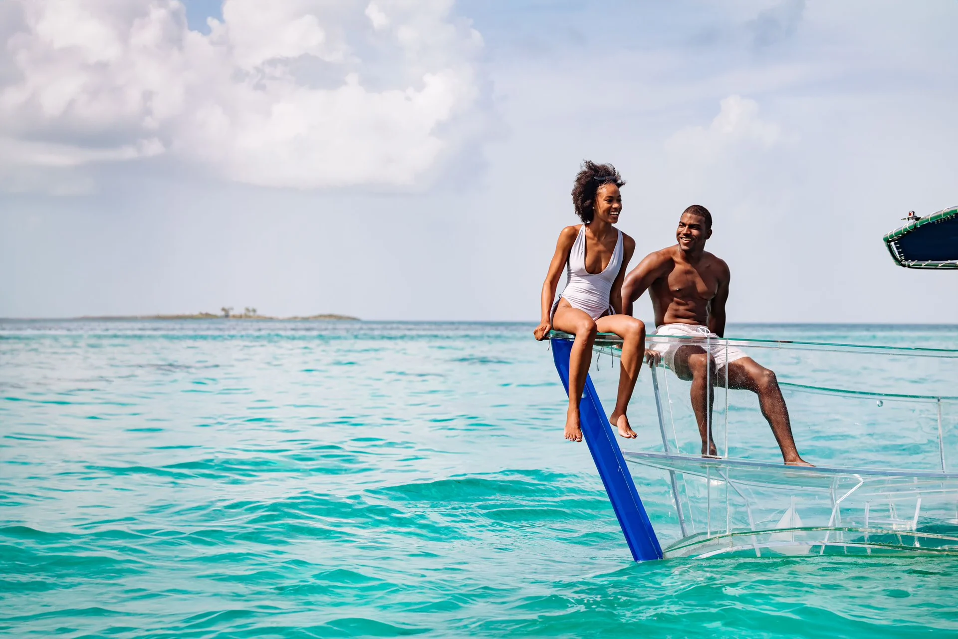 A couple enjoying Nassau’s turquoise water from a clear boat